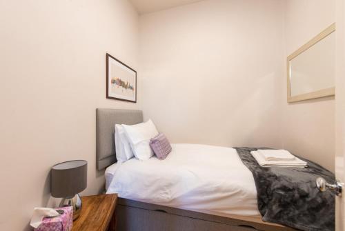 a small bedroom with a bed with white sheets at The Westfield in Edinburgh