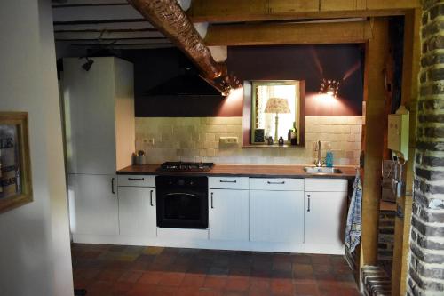 cocina con armarios blancos y estufa negra en Vakantiewoning Veurservallei, en Voeren