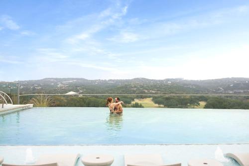 a man and a woman standing in the water in a swimming pool at Omni Barton Creek Resort and Spa Austin in Austin
