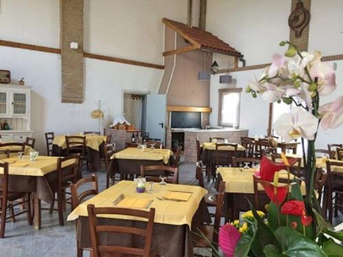 um restaurante com mesas e cadeiras de madeira e flores em Agriturismo Trava em Portoverrara