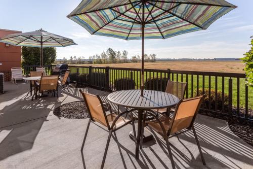 a patio with tables and chairs and an umbrella at Holiday Inn Express Hotel & Suites Bowling Green by IHG in Bowling Green
