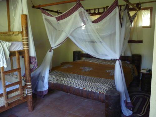 a bedroom with a canopy bed with mosquito nets at Bahari Pori Resort in Pangani