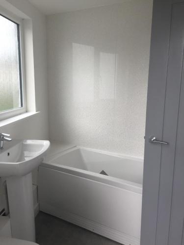 een witte badkamer met een bad en een wastafel bij Ogy1 Apartment - Apartment 1 in St Austell