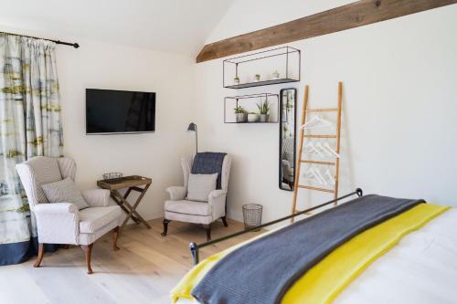 a bedroom with two chairs and a tv on a wall at Willow Barn Norfolk Broads B&B in Stokesby