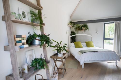 a bedroom with a bed with green pillows and plants at Willow Barn Norfolk Broads B&B in Stokesby