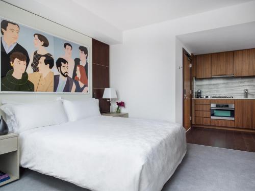 a bedroom with a large white bed and a kitchen at The Langham, New York, Fifth Avenue in New York