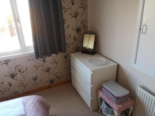 a small bedroom with a dresser and a mirror at Highland Home From Home in Inverness