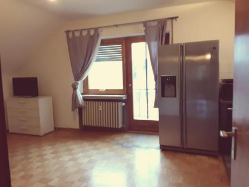 a kitchen with a refrigerator and a large window at Monteurwohnung - Business Apartment in Wertheim