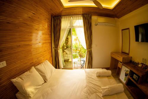 a bedroom with a large white bed with a window at PERLA Dhangethi in Dhangethi