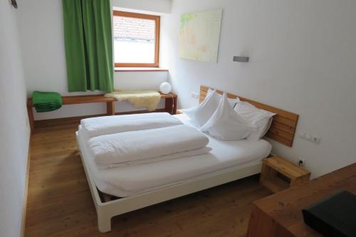 um quarto com uma cama com lençóis brancos e uma janela em aeki LOFT em Längenfeld