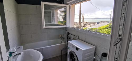 a bathroom with a sink and a washing machine and a window at Studio face à la mer in Concarneau