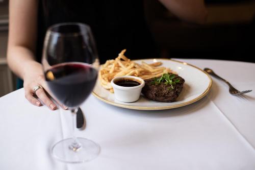 a person holding a glass of wine next to a plate of pasta at The Sebel Quay West Suites Sydney in Sydney