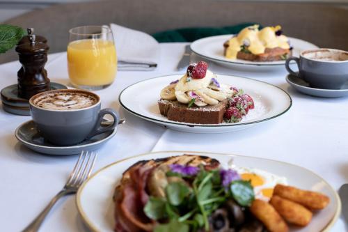 a table with plates of food and cups of coffee at The Sebel Quay West Suites Sydney in Sydney