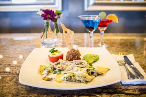 a white plate with food on a table with drinks at Holiday Inn Hotel & Suites Hermosillo Aeropuerto by IHG in Hermosillo
