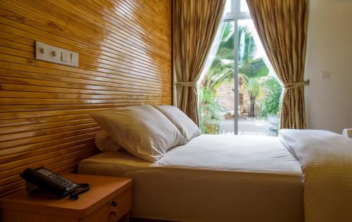 a bedroom with a bed and a phone on a table at PERLA Dhangethi in Dhangethi