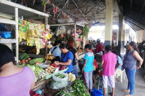 a group of people standing around a market with vegetables at The balcony of the camiguin island in Mambajao