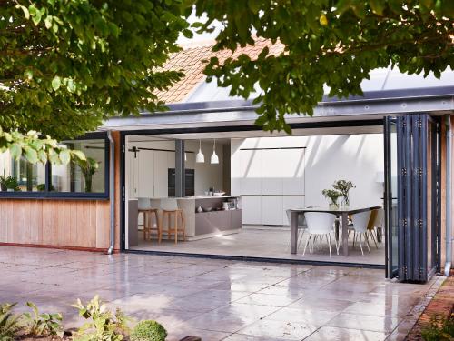 an open kitchen and dining room of a house with sliding glass doors at Willow Barn Norfolk Broads B&B in Stokesby