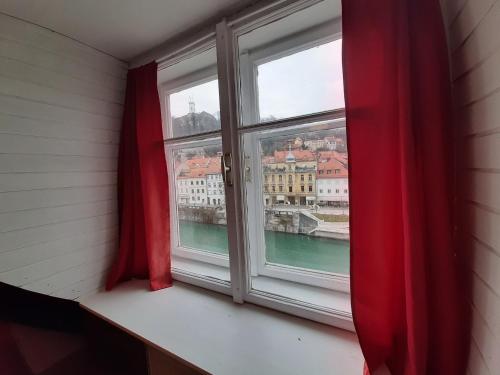 ein Fenster mit roten Vorhängen und Stadtblick in der Unterkunft VIKSI hostel in Ljubljana
