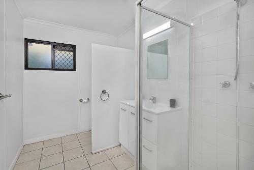 a white bathroom with a shower and a sink at The Red Sparrow 2 in Cairns