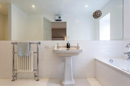 a white bathroom with a sink and a bath tub at The Billiards Room in Queenstown