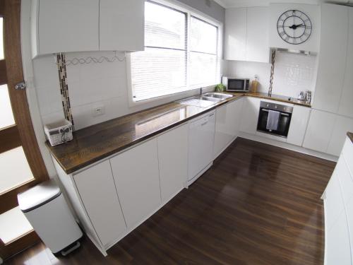 a kitchen with white cabinets and a clock on the wall at The Beardman Armidale in Armidale