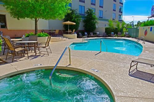 een zwembad met stoelen en een tafel en een gebouw bij Holiday Inn Phoenix Airport, an IHG Hotel in Phoenix