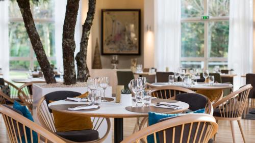 ein Restaurant mit Tischen und Stühlen und Fenstern in der Unterkunft Holiday Inn Resort le Touquet by IHG in Le Touquet-Paris-Plage