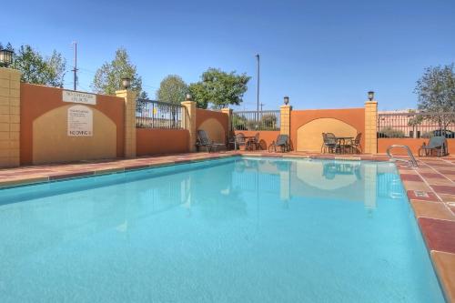 a swimming pool at a resort with tables and chairs at Holiday Inn Express Hotel & Suites Albuquerque Midtown by IHG in Albuquerque