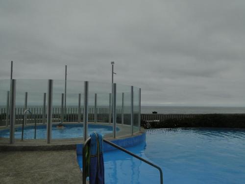 a swimming pool next to a beach with the ocean at Condominio Arena Maris in Algarrobo