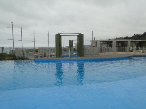 a large swimming pool with a swing set in the water at Condominio Arena Maris in Algarrobo