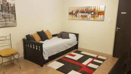 1 dormitorio con cama con almohadas y alfombra en Temporarios B & B 2 en San Salvador de Jujuy