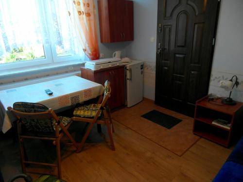 a kitchen with a table and two chairs and a door at Mieszkanie Wakacyjne Adam in Chmielno