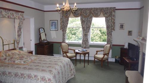 a bedroom with a bed and a table and chairs at Leadon House Hotel in Ledbury