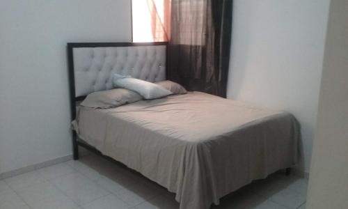 - un petit lit dans une chambre avec fenêtre dans l'établissement Amplio y acogedor apartamento, à Santiago de los Caballeros