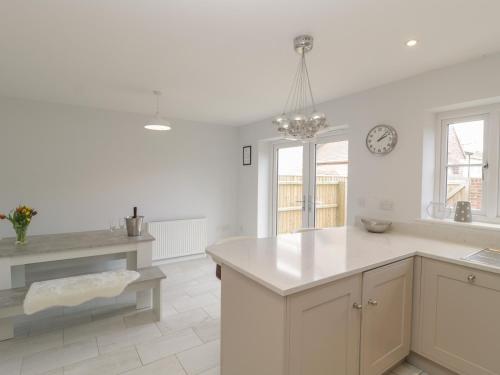 a kitchen with white counters and a clock on the wall at 1 Sutton Gate in Weymouth