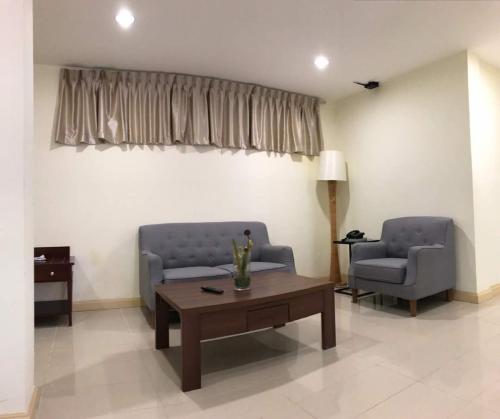 a living room with two chairs and a coffee table at The Capital Residence Suites in Bandar Seri Begawan