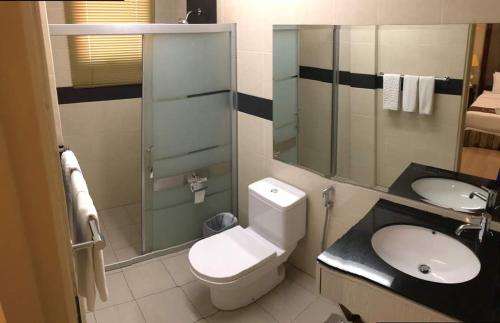 a bathroom with a toilet and a sink and a mirror at The Capital Residence Suites in Bandar Seri Begawan