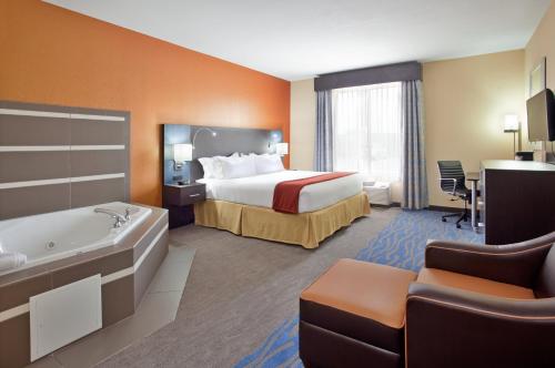 a hotel room with a bed and a bath tub at Holiday Inn Express & Suites St Louis Airport by IHG in Woodson Terrace