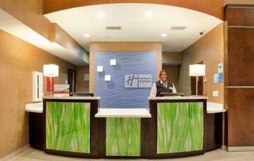 a woman standing at a podium in a lobby at Holiday Inn Express & Suites St Louis Airport by IHG in Woodson Terrace