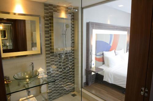 a bathroom with a shower and a bed and a sink at Novotel Bangkok IMPACT in Nonthaburi