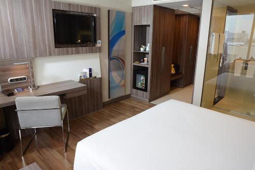 a room with a bed and a desk and a television at Novotel Bangkok IMPACT in Nonthaburi