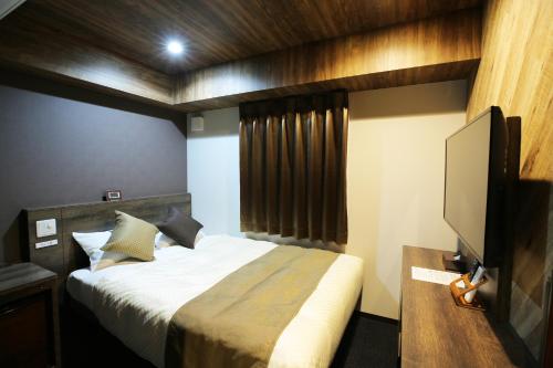 een slaapkamer met een bed en een flatscreen-tv bij The Celecton Matsumoto in Matsumoto