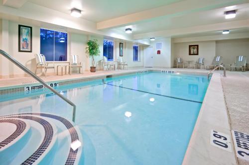 einen Pool in einem Hotel mit Stühlen und Tischen in der Unterkunft Holiday Inn Express Hotel & Suites Clifton Park, an IHG Hotel in Clifton Park