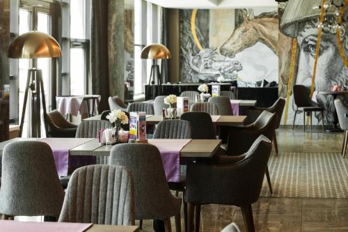 イルクーツクにあるBaikal Business Center Hotelのテーブルと椅子、馬の壁画のあるレストラン