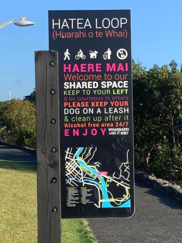 a sign in a park with a lizard on it at Beach Lane Apartment in Whangarei