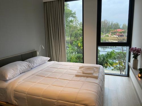 a bedroom with a bed and a large window at Cassia Apartment 1 in Bang Tao Beach