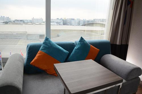 a blue couch with orange and blue pillows and a table at Novotel Bangkok IMPACT in Nonthaburi