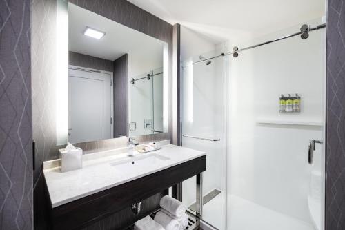 a bathroom with a sink and a shower and a mirror at Staybridge Suites - Quincy by IHG in Quincy