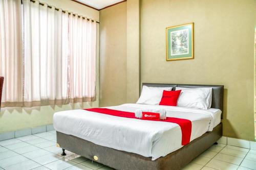 una camera da letto con un grande letto con cuscini rossi di RedDoorz near Plaza Senayan a Giacarta