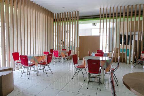a dining room with red chairs and a table at Hotel Taman Indah in Madiun